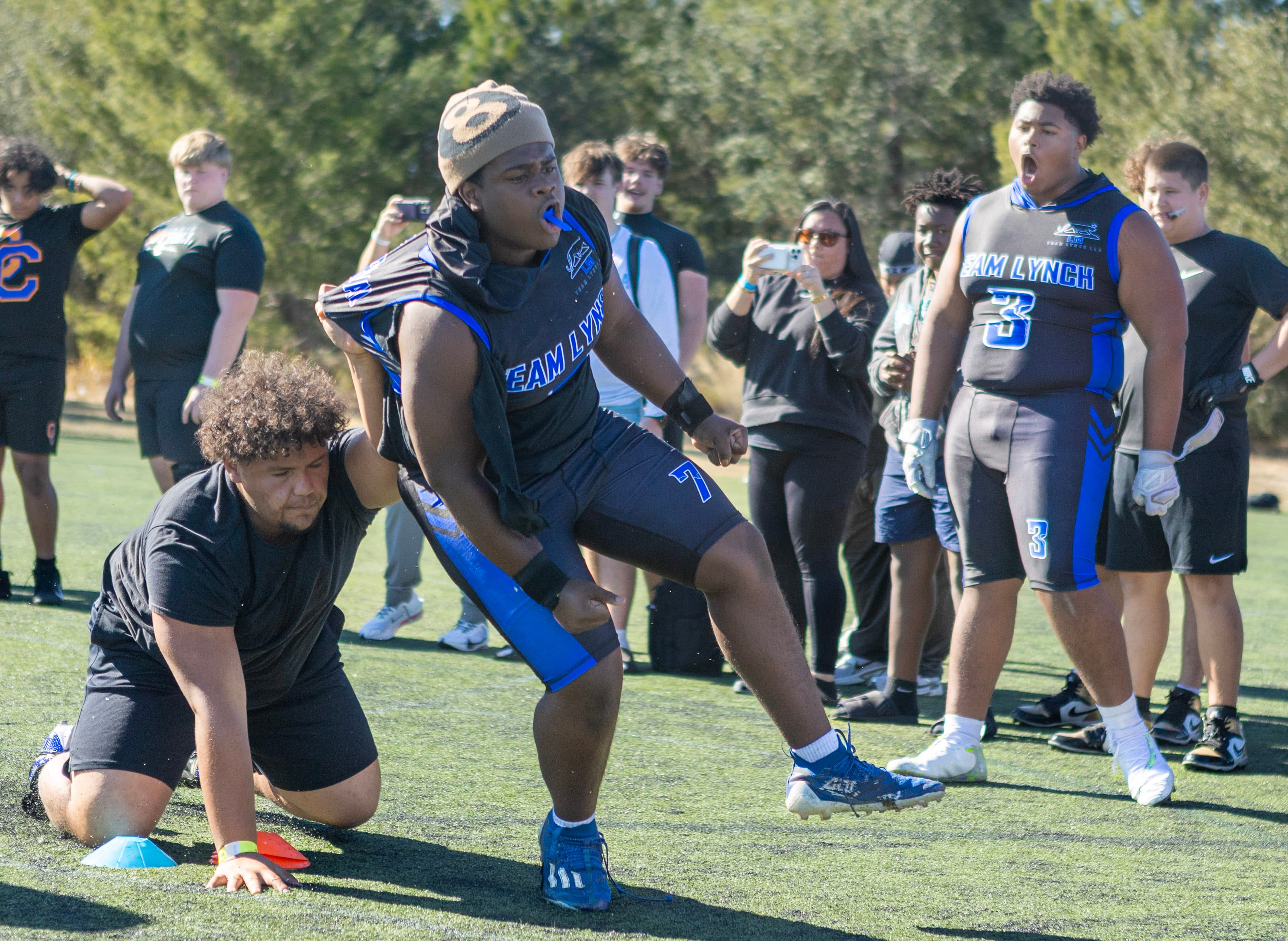 Athletes during a football agility drill with teammates and spectators